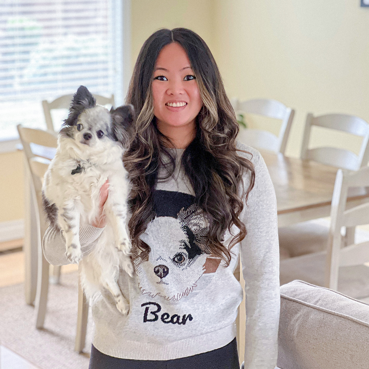 Woman wearing a sweater with a large illustration of a small white and black dog on the front.