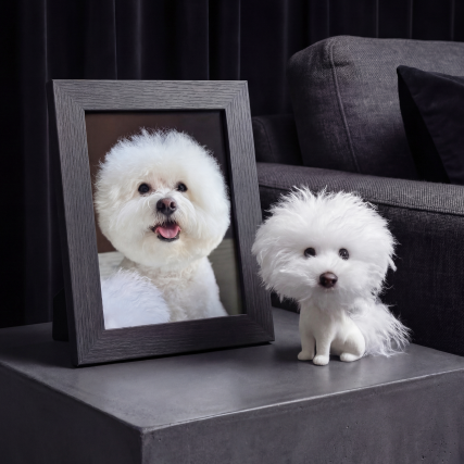 Framed Bichon Frisé photo beside a matching custom bobblehead on a wooden side table.