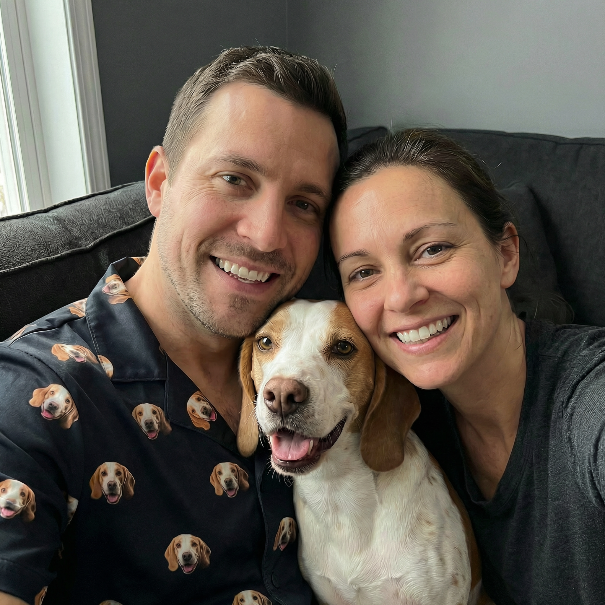 Couple smiling with a dog in the center, the man is wearing a pajama.