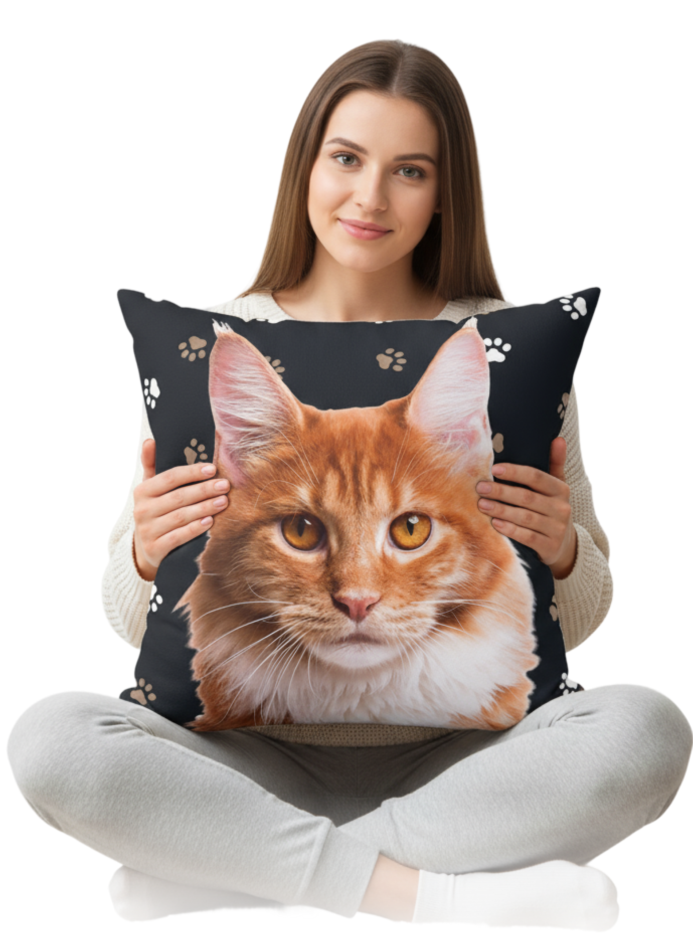 A young woman with long brown hair sits cross-legged on a light gray background, smiling while holding a large square throw pillow with a cat face. 