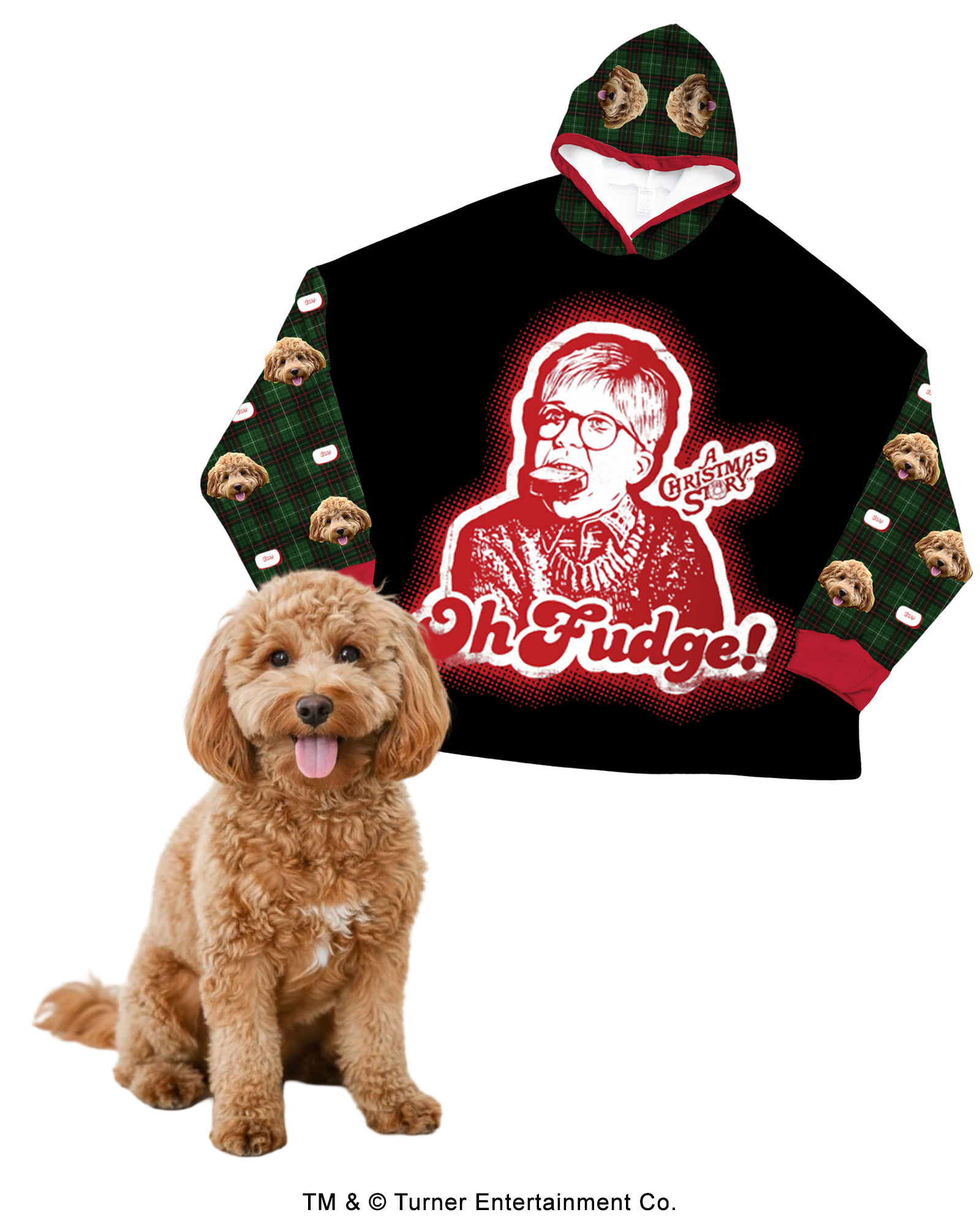 An oversized, black hooded blanket featuring a large central red and white graphic of Ralphie from A Christmas Story with soap in his mouth, alongside the quote 'Oh Fudge!' The sleeves and hood lining feature a green, black, and red plaid pattern. The plaid is customized with a repeating design of a fluffy brown Cockapoo's face. A real Cockapoo dog sits in the foreground.