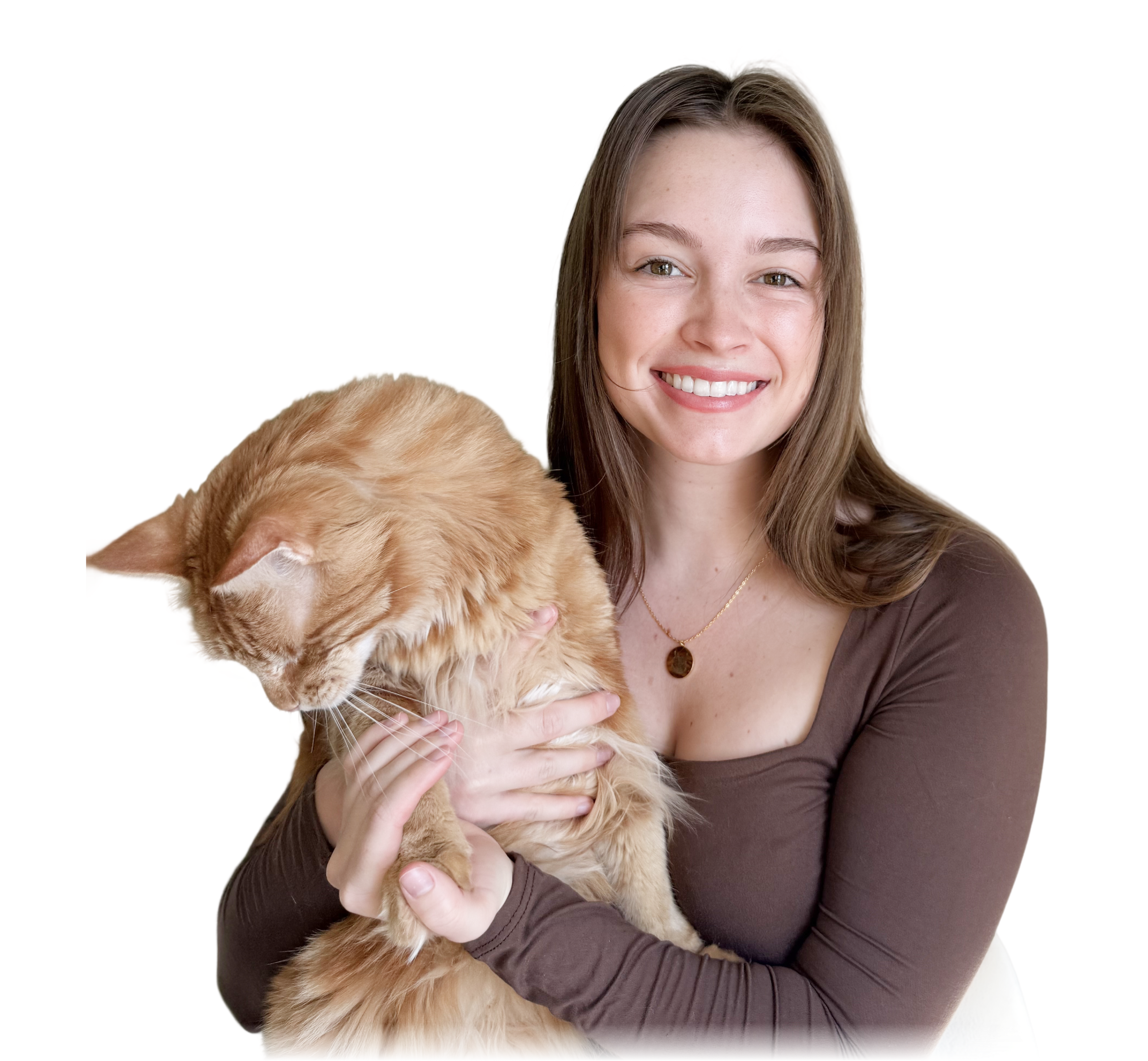 A smiling woman with long brown hair holds a very large, fluffy orange Maine Coon cat that is looking down. The woman is wearing a brown, long-sleeved top and a delicate gold chain necklace with a circular pendant that features a pet portrait.