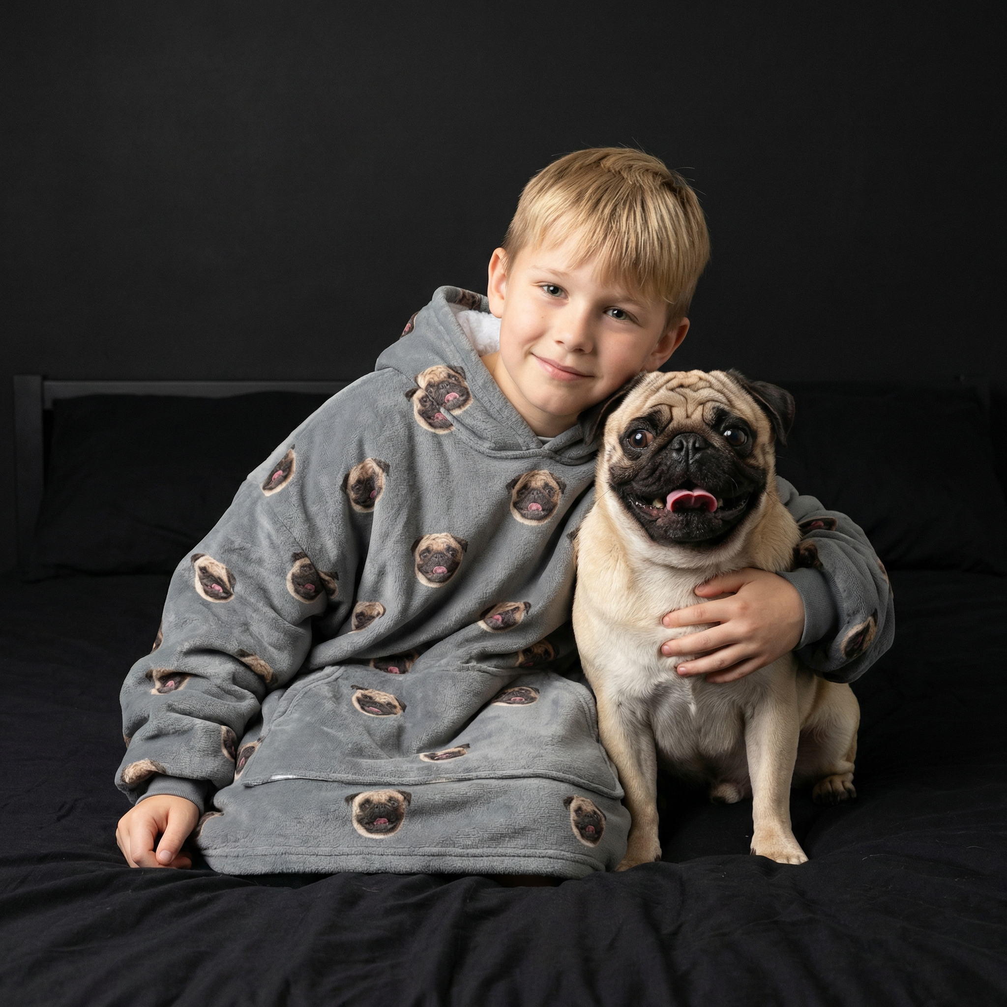 Kid wearing a blanket hoodie next to his pug.