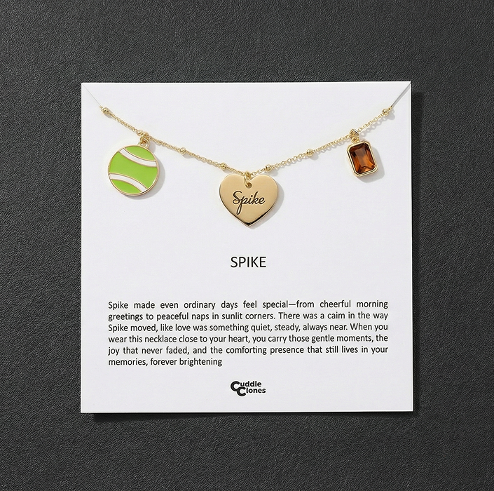 Gold necklace with tennis ball, heart, and rectangular charms on display card.