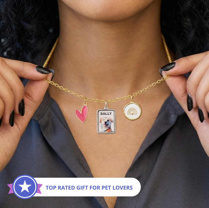 Woman wearing gold charm necklace with heart, dog photo, and rainbow pendant on neck