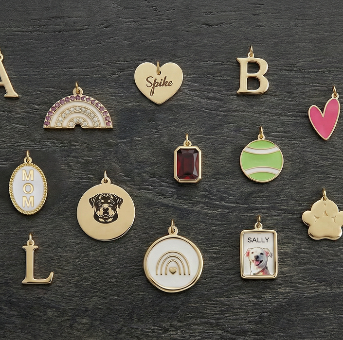 Various gold and colorful charms on a dark surface, including hearts, letters, and shapes.