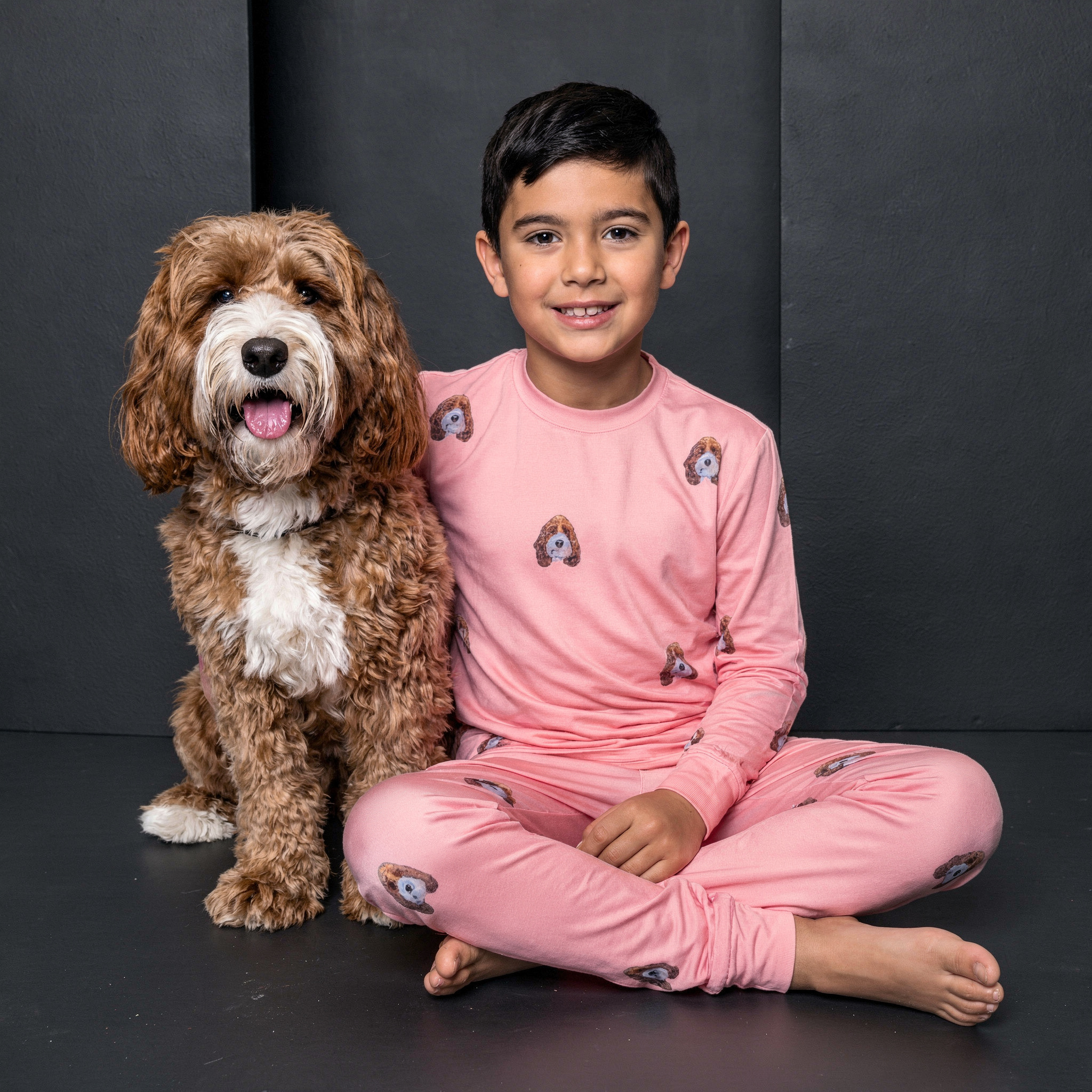 Kid wearing a pin pajama next to a dog.