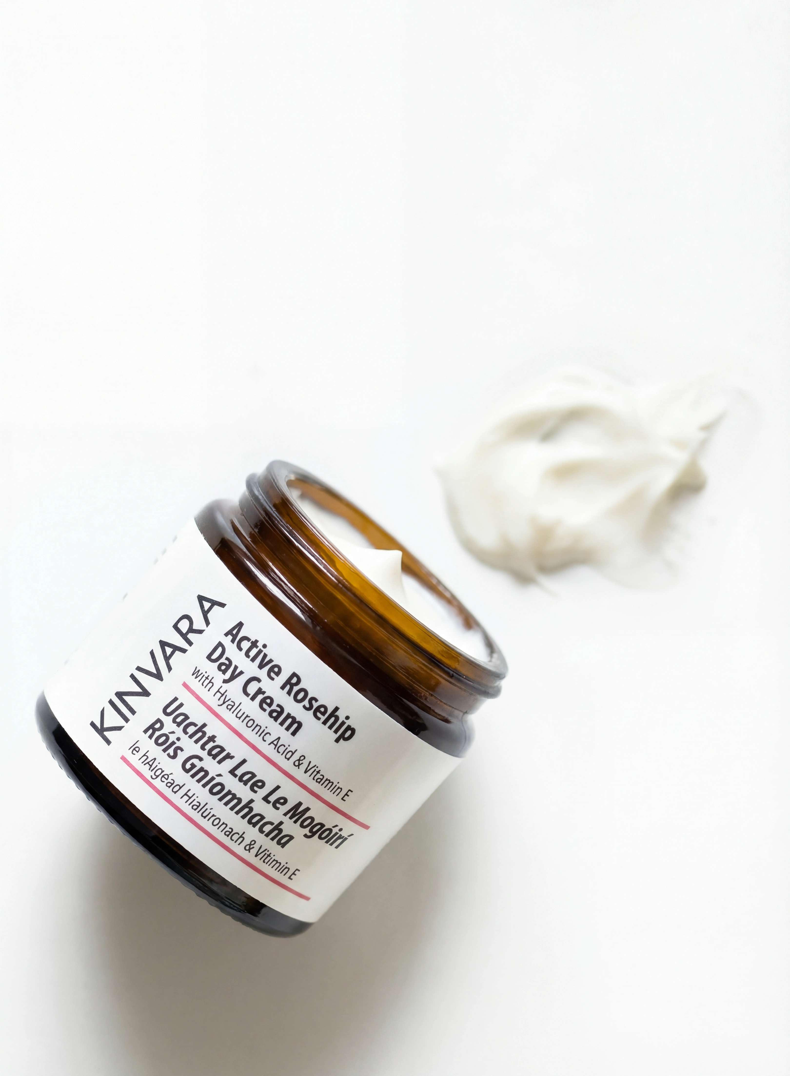 A brown glass jar of Kinvara Active Rosehip Day Cream with a smear of cream beside it.