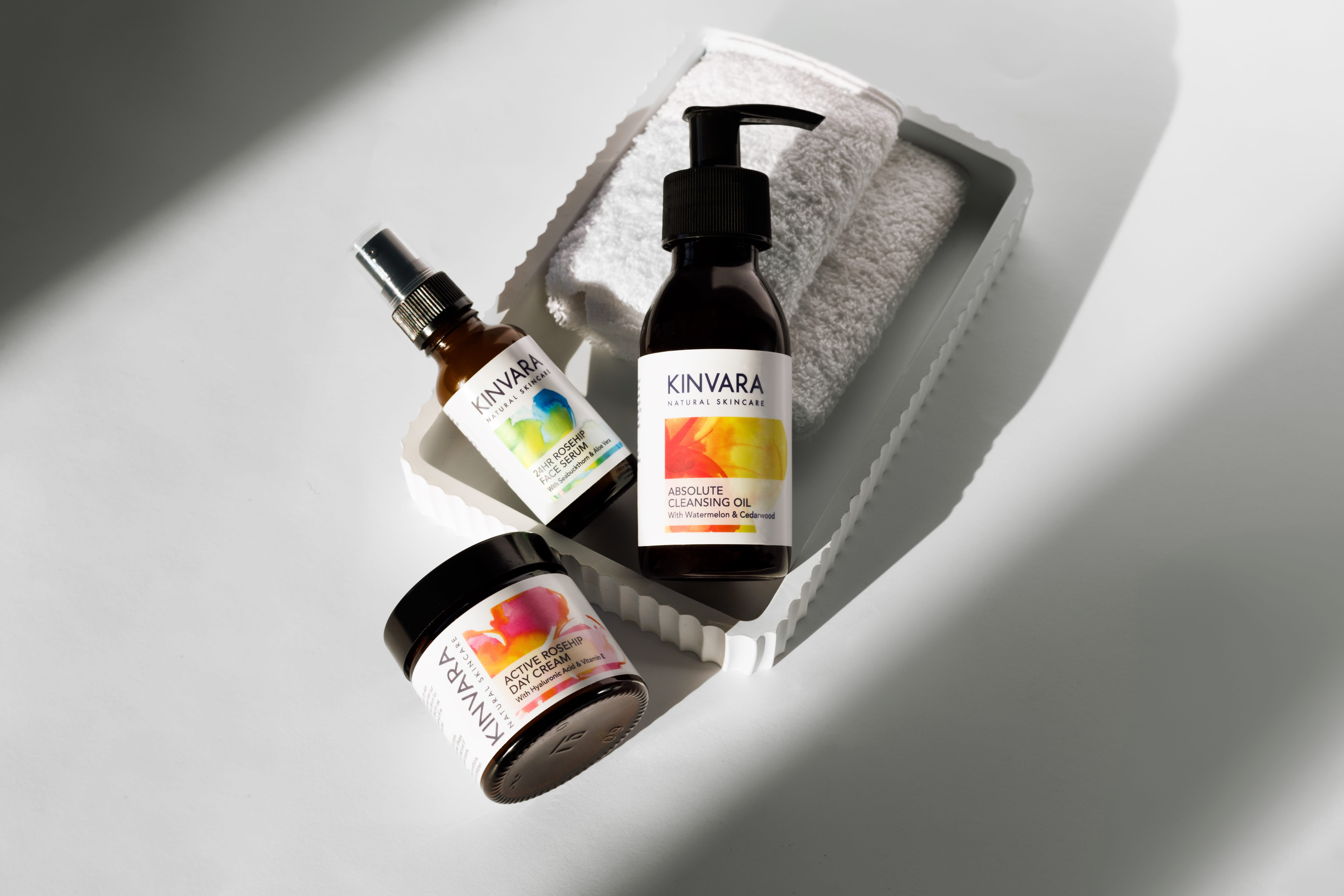Skincare products with a towel on a white tray, in soft lighting.