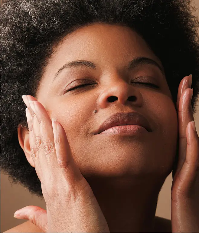 Person with eyes closed, gently touching face with both hands.
