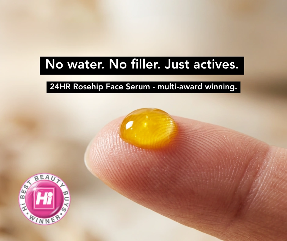 A close-up of a drop of golden rosehip face serum on a fingertip, with an award winner logo.