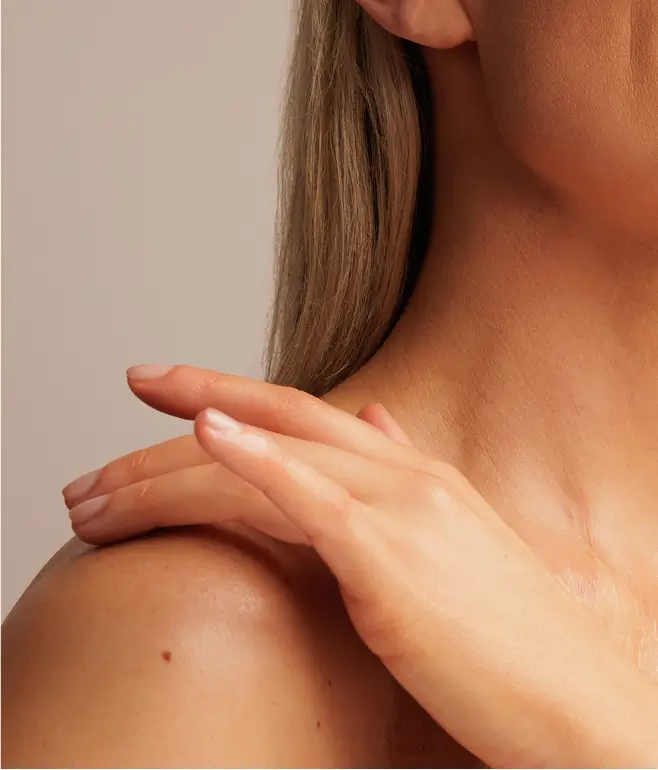 Close-up of a person touching their shoulder with one hand.