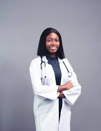 Person in a white coat with a stethoscope, smiling against a gray background.