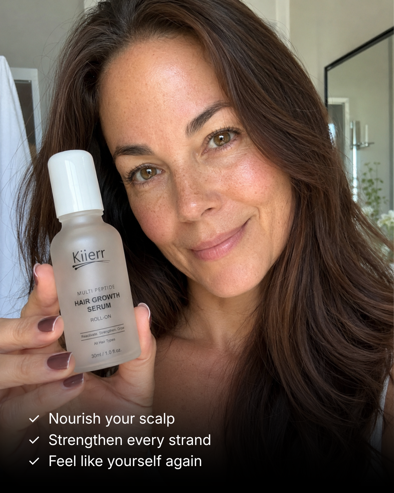 A smiling woman with brown hair holds up a bottle of Kiierr Multi Peptide Hair Growth Serum.