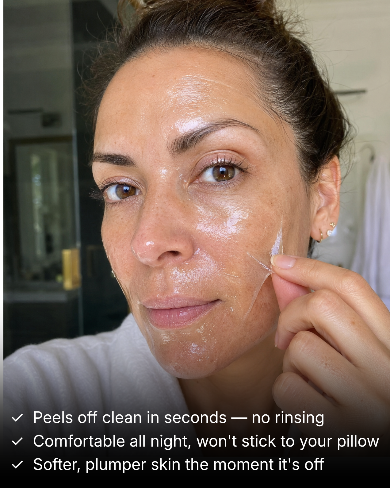 A woman in a white robe peels a clear, gel-like mask from her cheek.