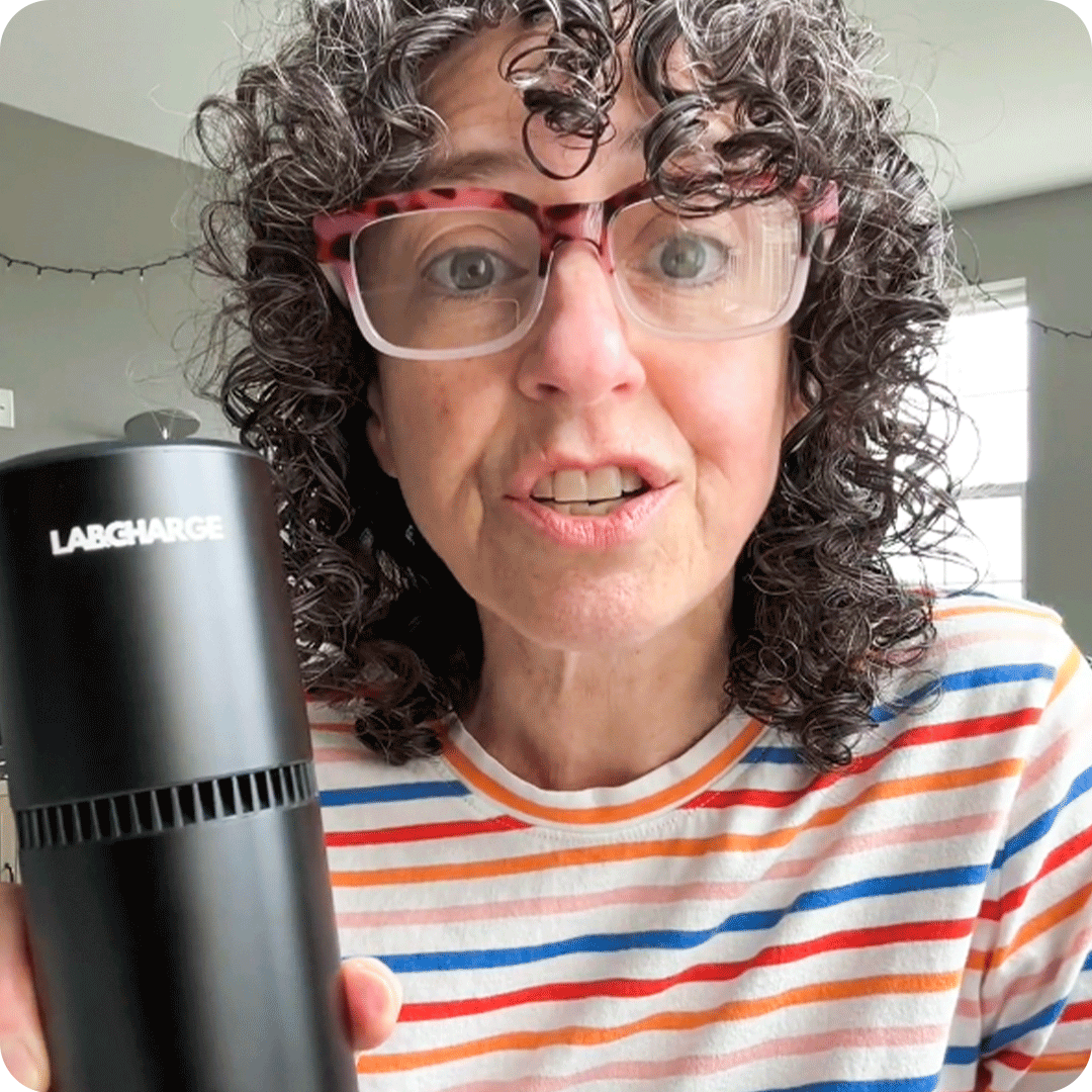 A woman sitting at a table holding a LabCharge device.