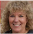 Smiling person with curly hair in an outdoor setting.