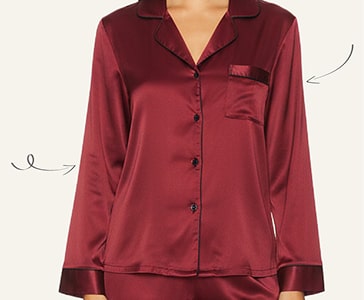 Person wearing a red satin pajama top with a chest pocket and black buttons.