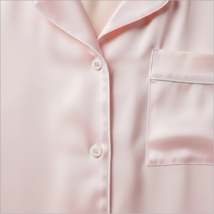 Close-up of a pink satin shirt with buttons and a pocket.