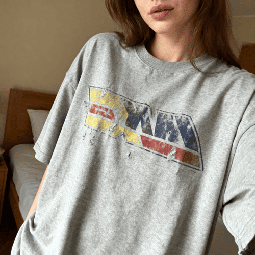 Person wearing a gray t-shirt with a faded graphic design.