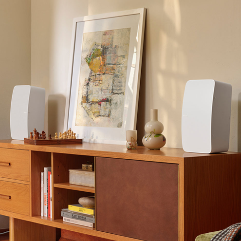 Wooden sideboard with speakers, abstract art, and decorative items.