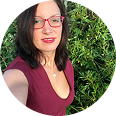 Person wearing glasses with greenery in the background.
