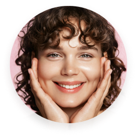 Person smiling with hands framing face, curly hair, pink background.