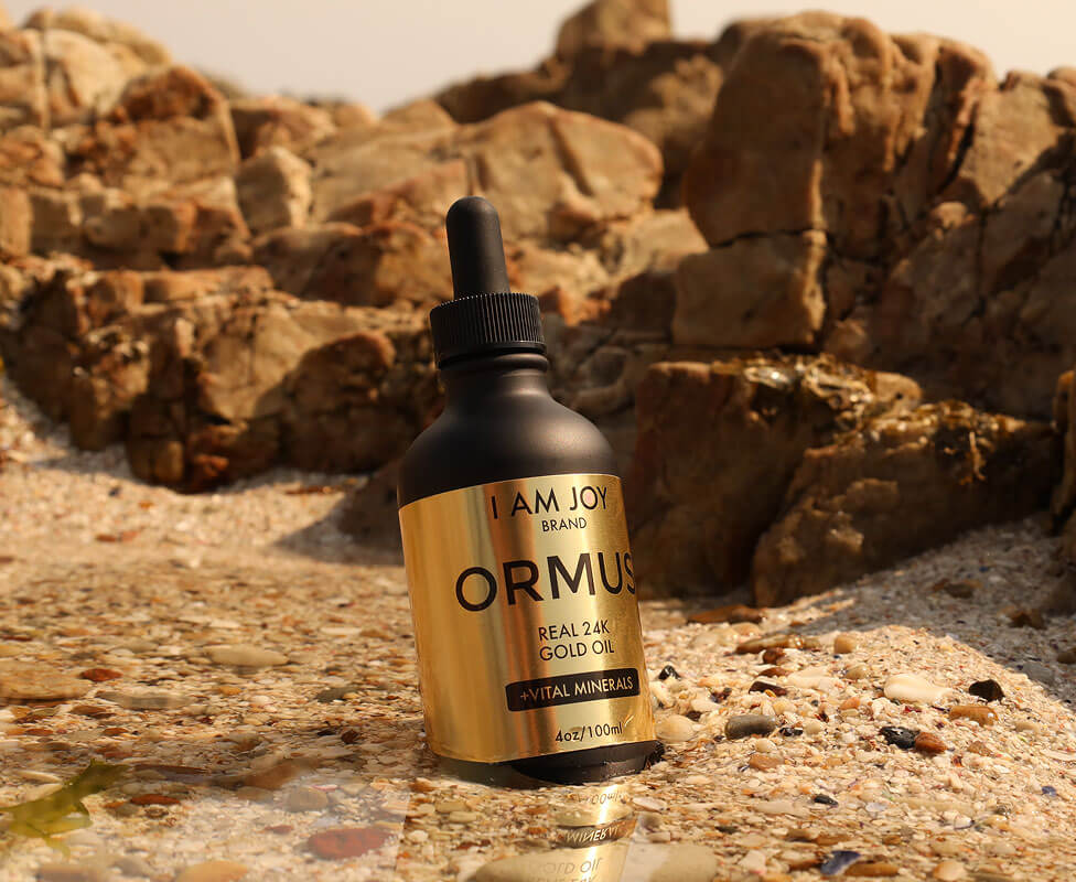 Bottle of Ormus gold oil on a rocky beach.