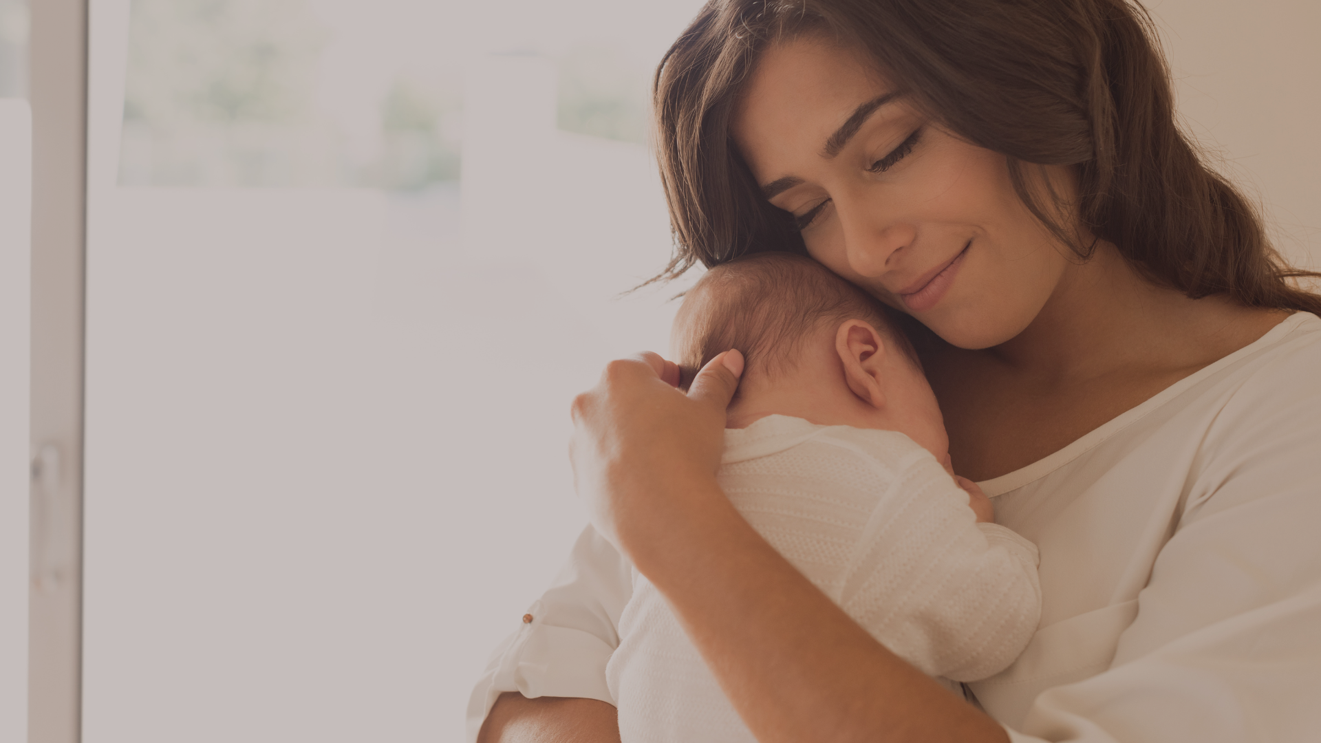Woman gently holding a sleeping baby close to her chest.
