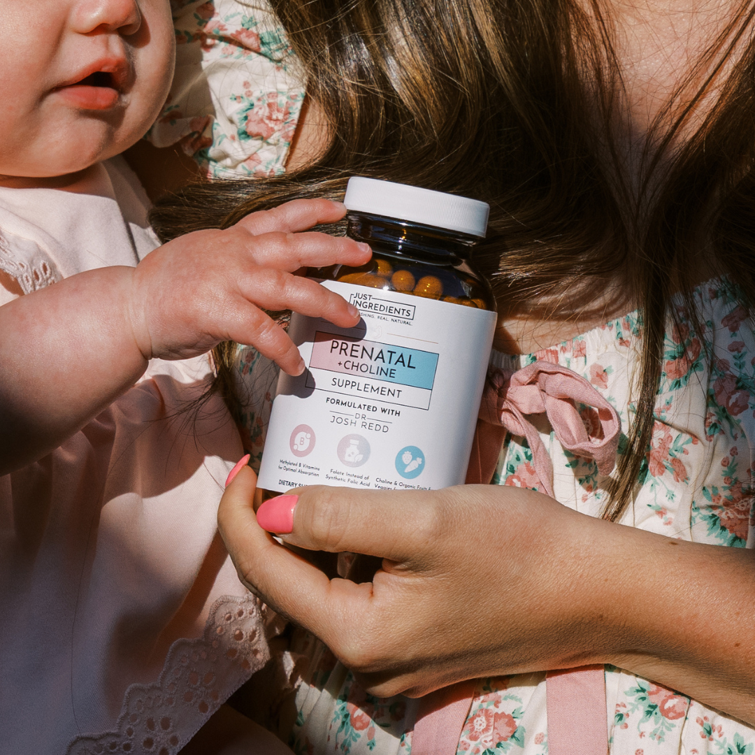 Baby holding a bottle of prenatal choline supplement with an adult.