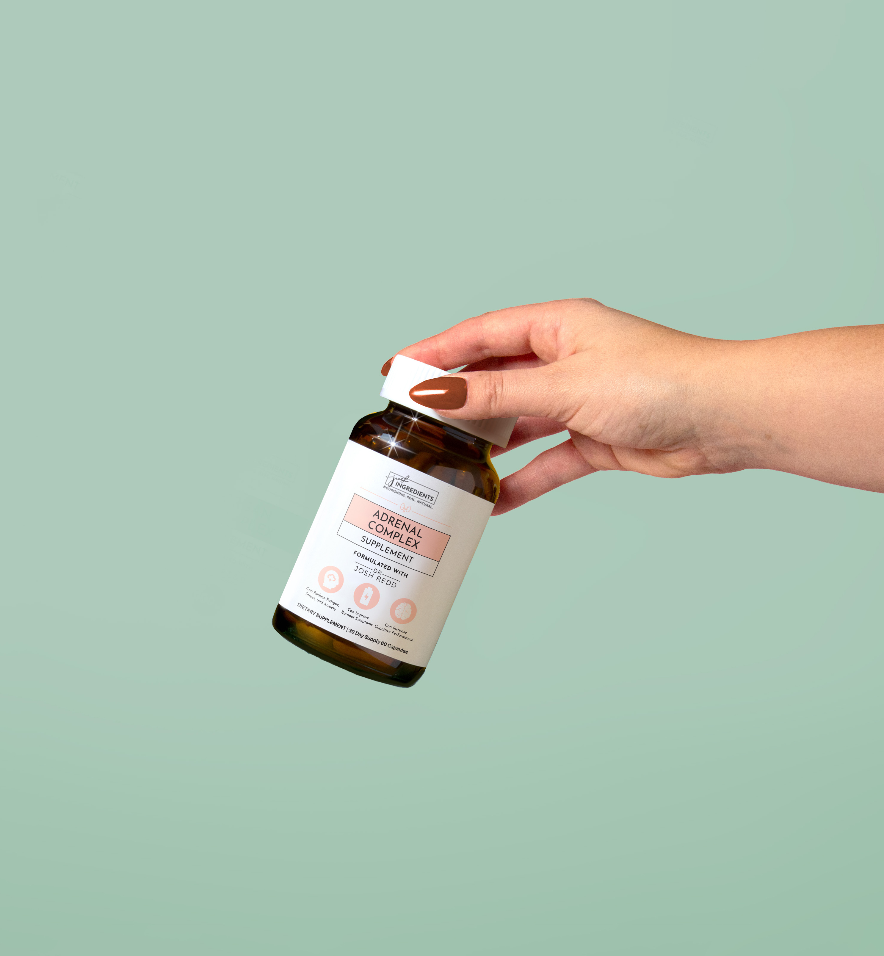 Hand holding a bottle of adrenal complex supplement against a green background.