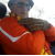 Person wearing an orange jacket and brown gloves inside a vehicle.