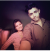 Two people smiling and posing for a selfie in dim lighting.