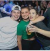 Three people smiling and posing for a photo at a lively social event.