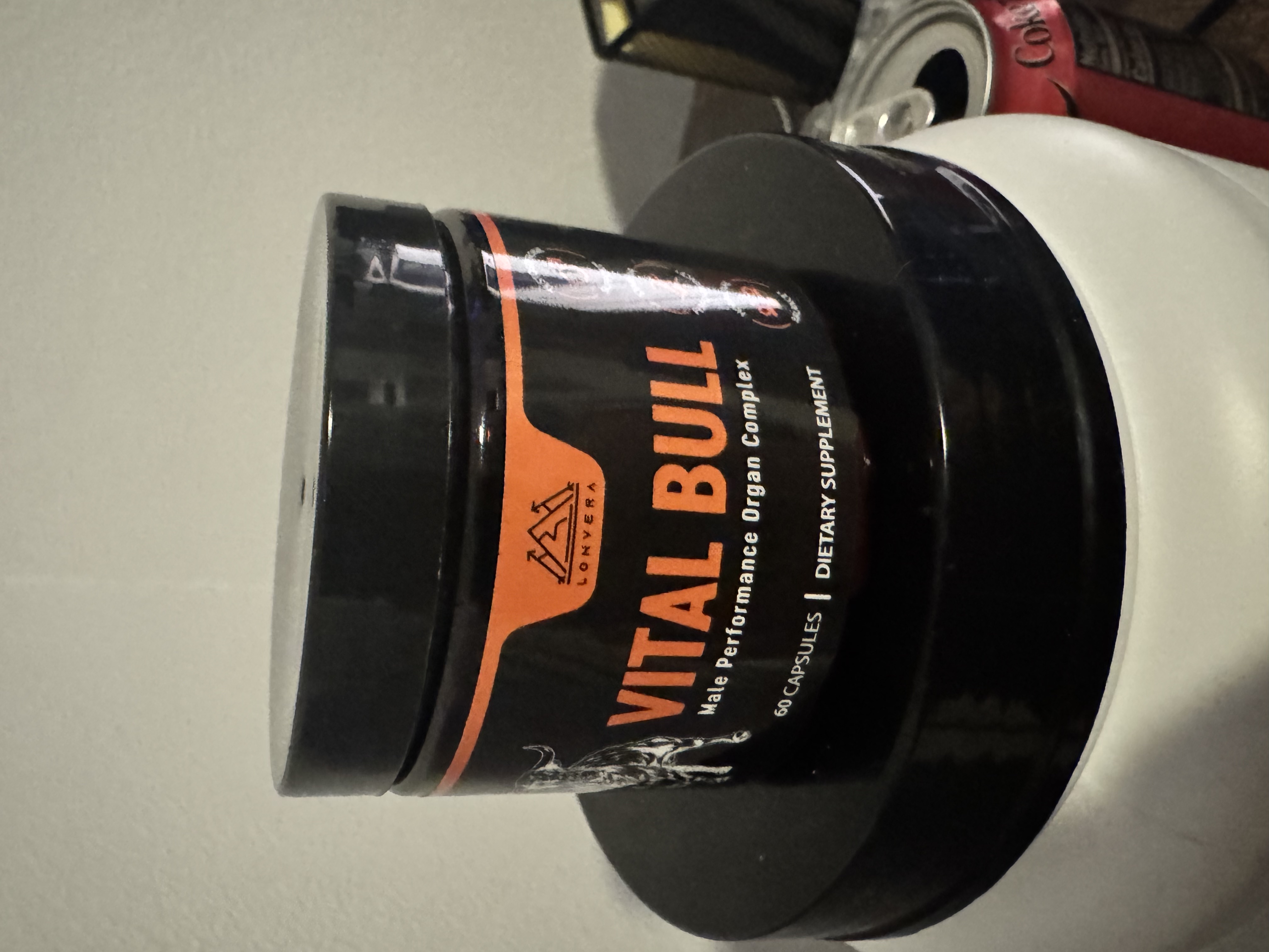 Black container labeled 'Vital Bull' dietary supplement on a white surface.