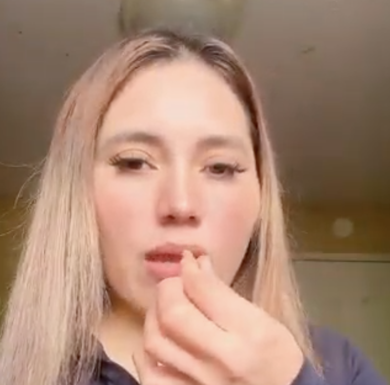 Person with long hair holding something near their mouth.