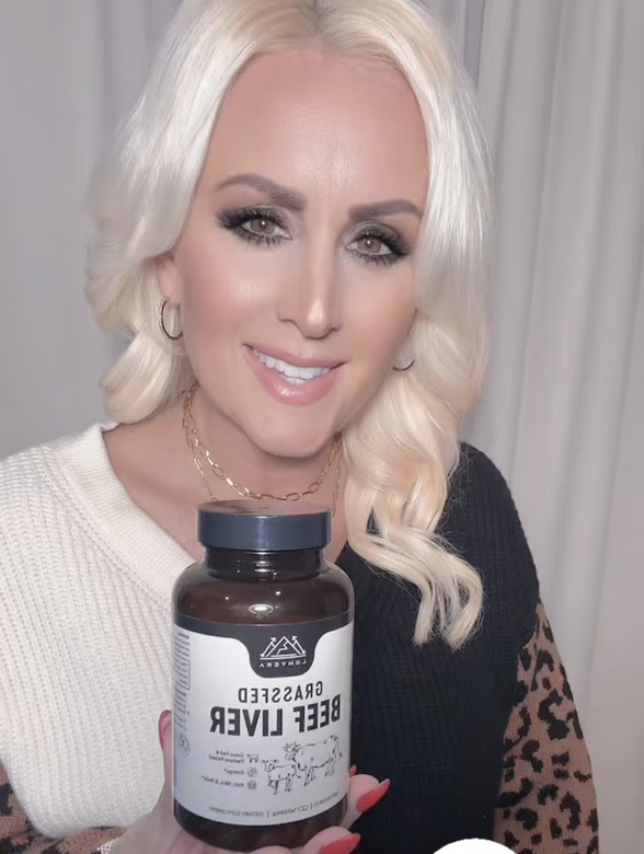 Person holding a bottle labeled 'Grassfed Beef Liver' with a smile.