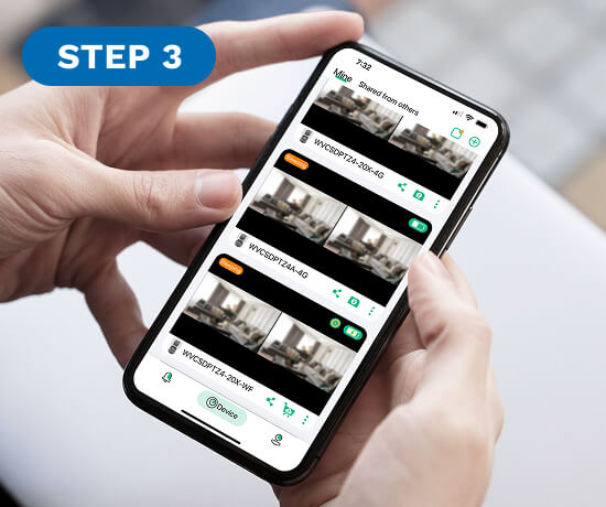 Person holding a smartphone displaying a list of video thumbnails.