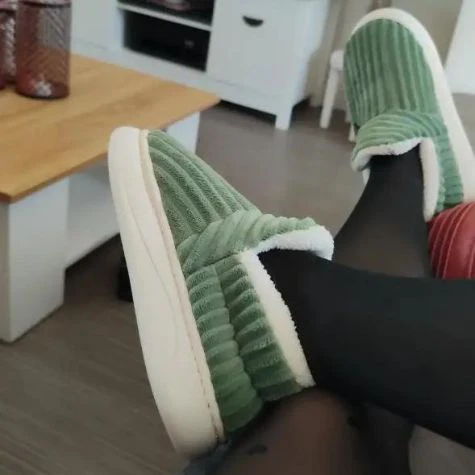 Green slippers on feet with a wooden table in the background.