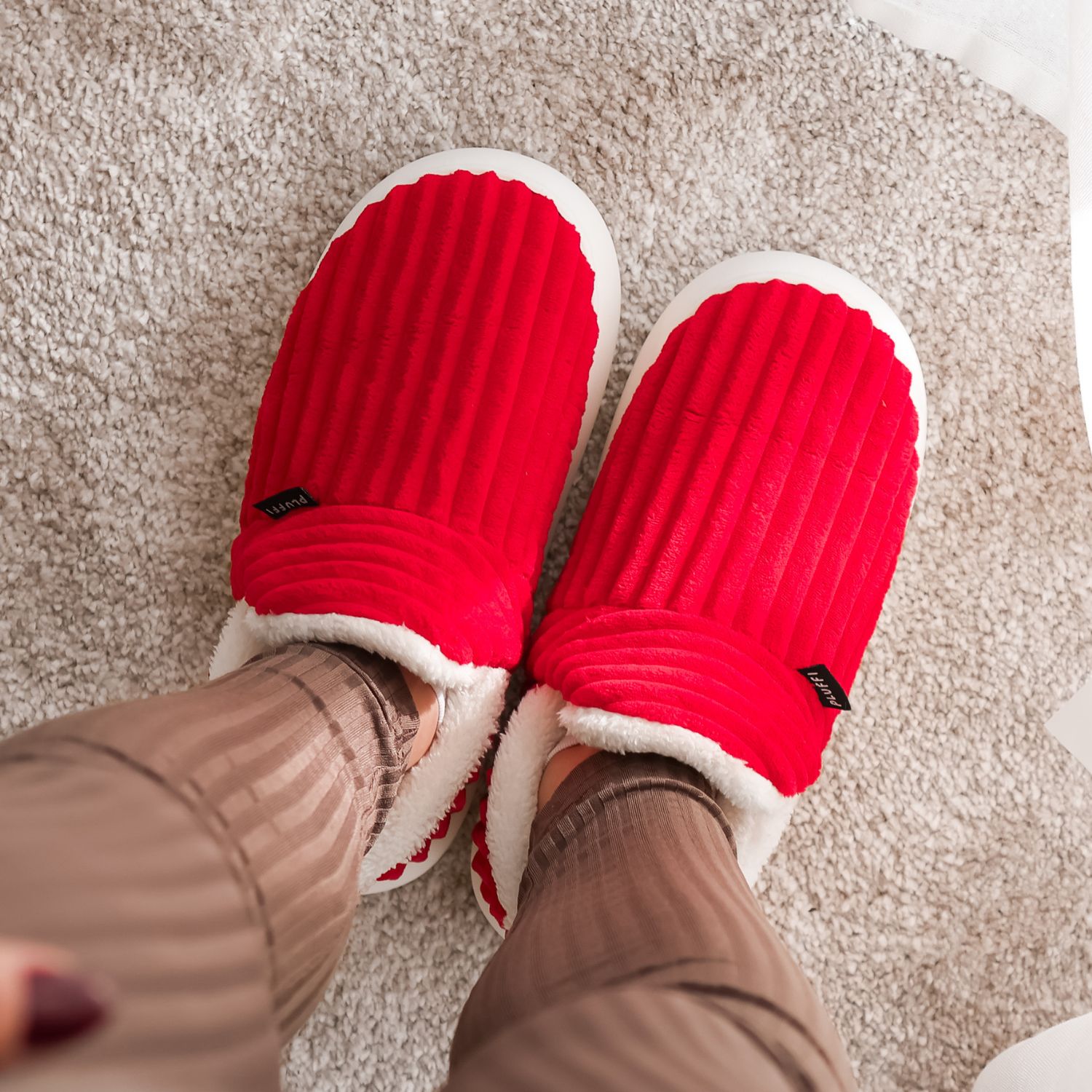 Person wearing red slippers with white trim on a carpet.
