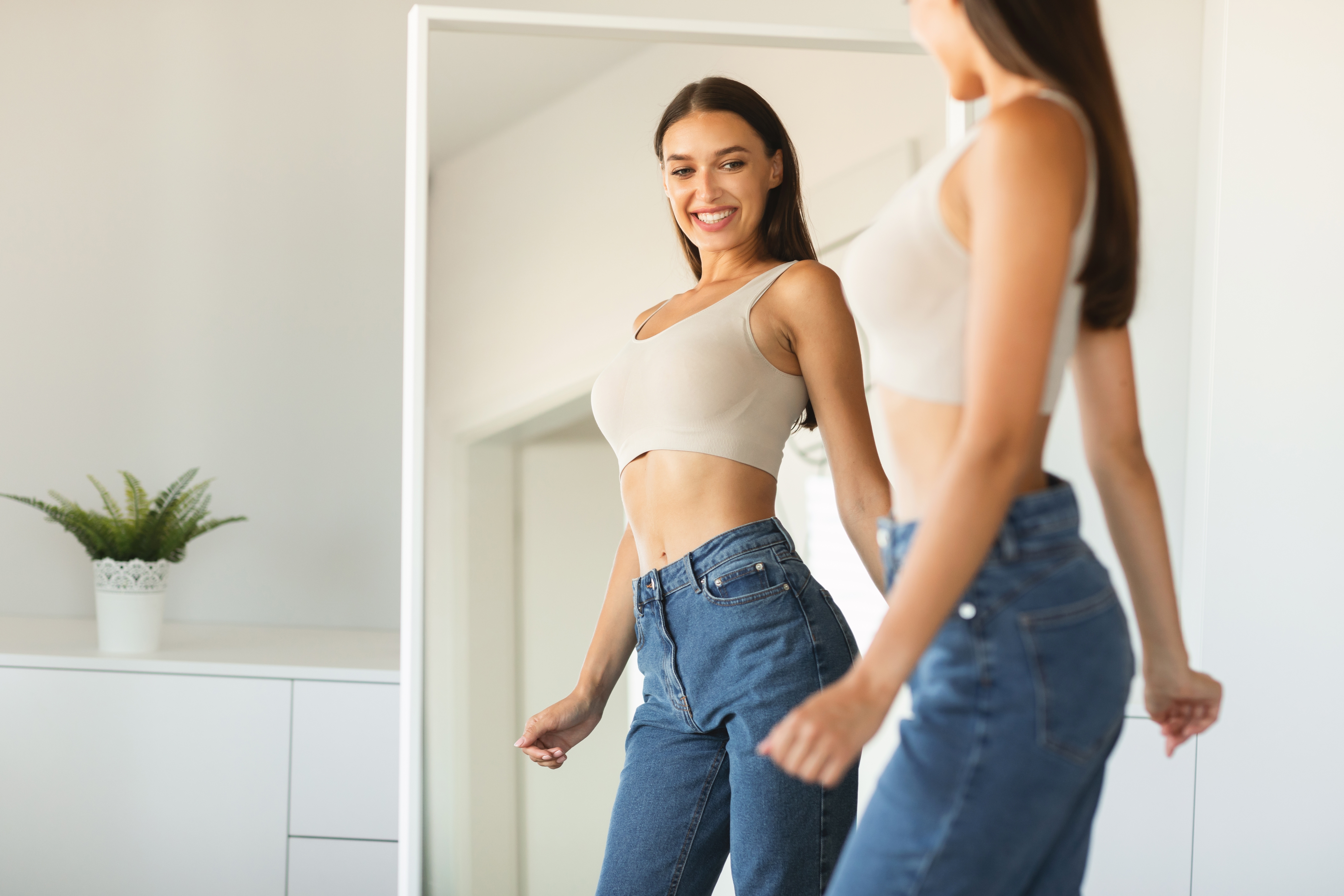 Woman smiling at mirror in casual outfit.