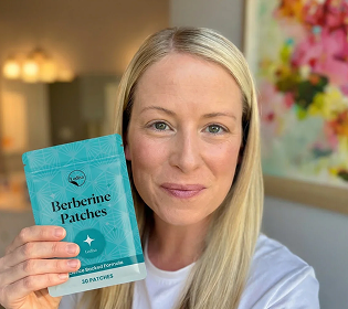 A blonde woman with her hair down, holding a teal pouch of Berberine Patches.