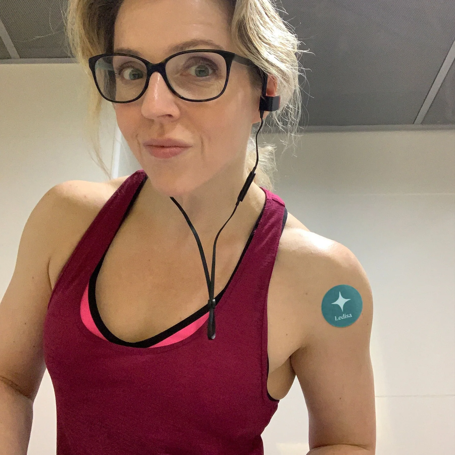 Person wearing glasses and headphones, with a sticker on their shoulder.