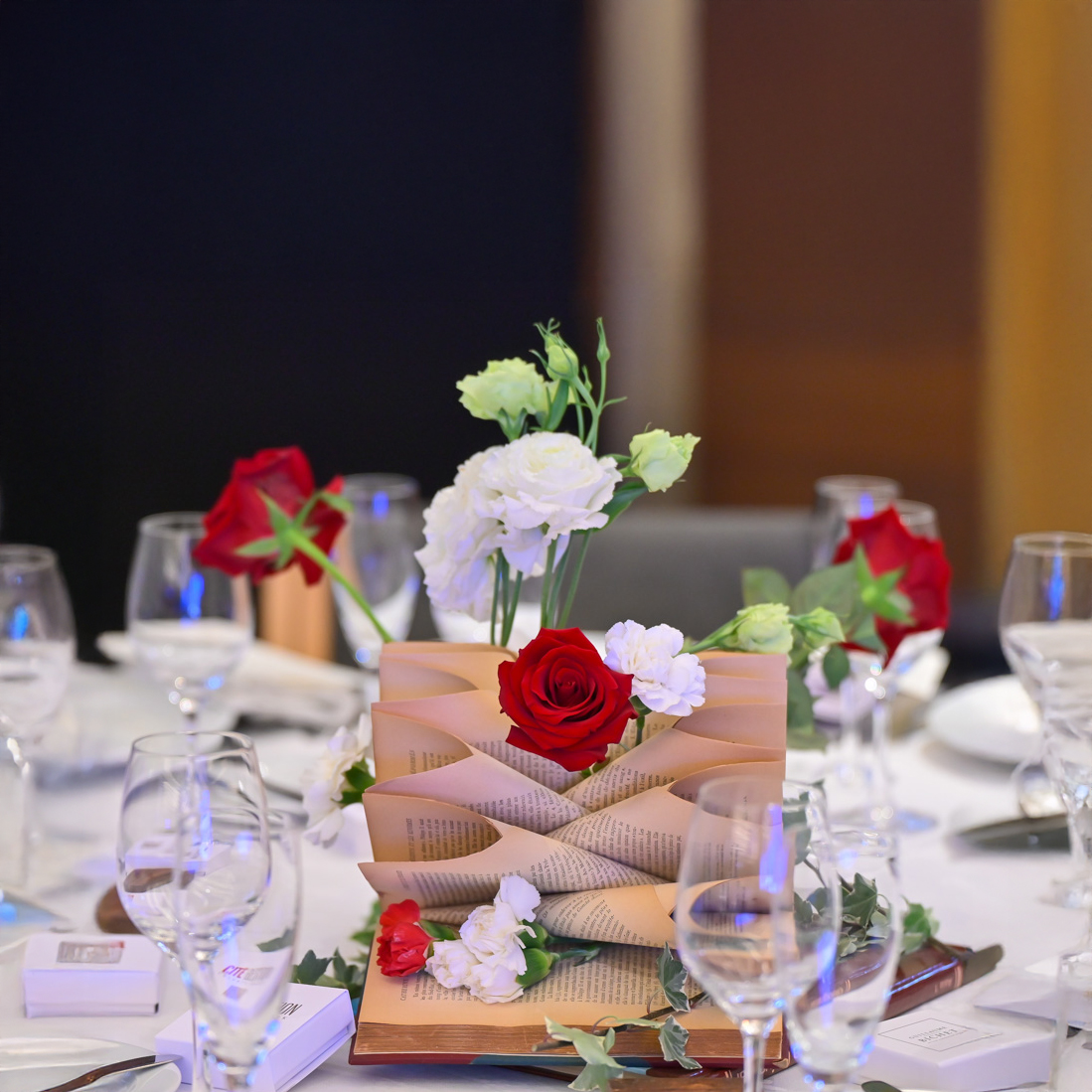 Table centerpiece with open book and red, white flowers.