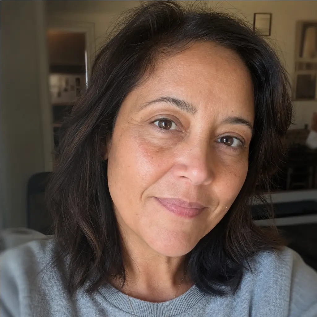 A woman with shoulder-length dark hair and brown eyes smiles gently while wearing a gray sweater.