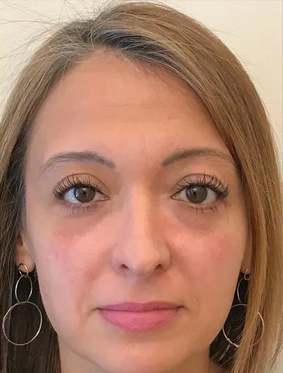 A woman with hoop earrings and straight hair looking directly at the camera.