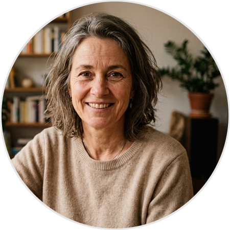 A smiling woman with wavy, graying hair and a beige sweater, in a circular frame.