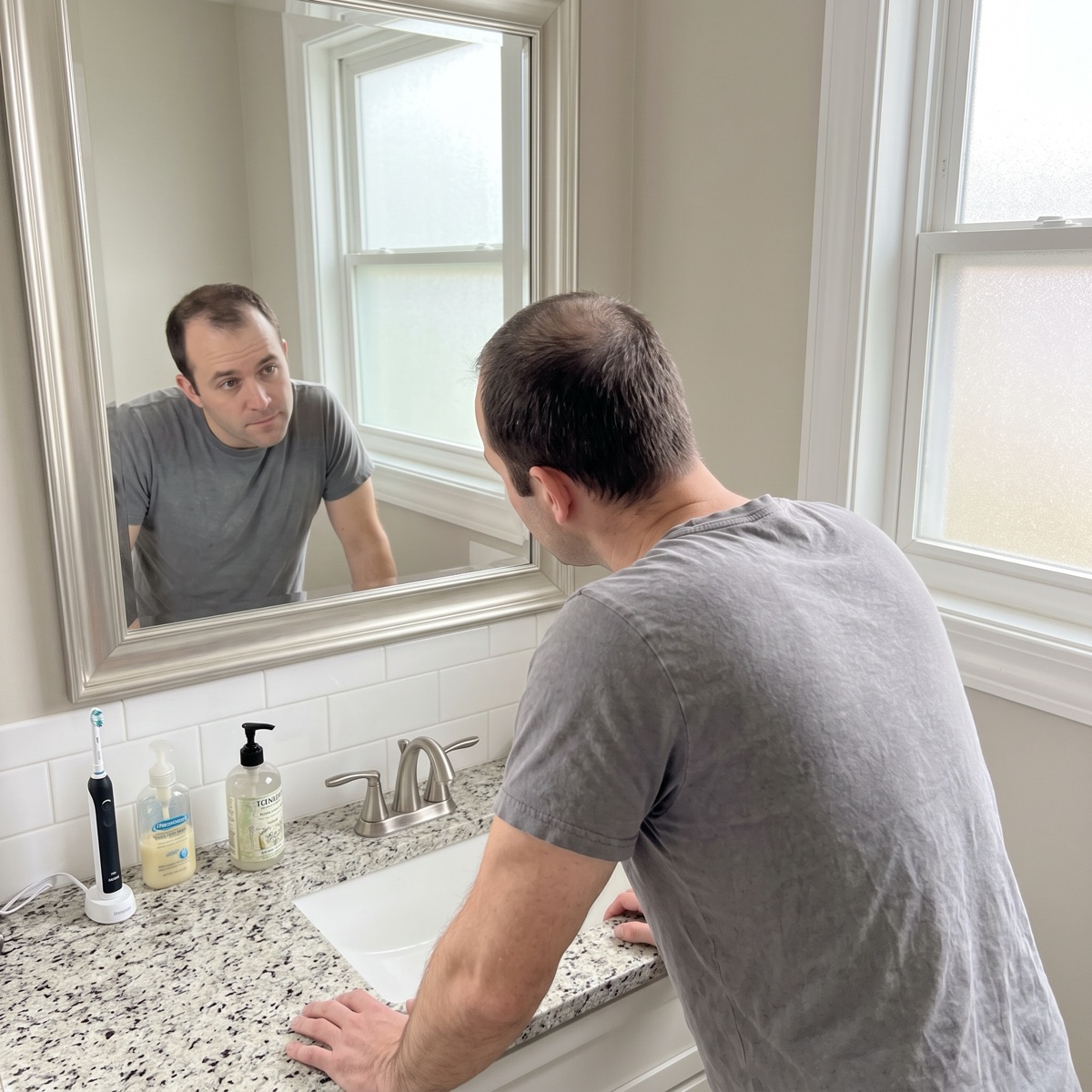 Man looking at his thinning crown in the mirror