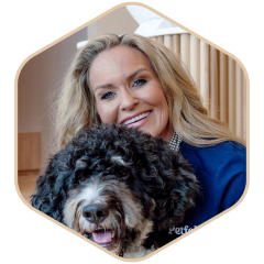 A person smiling and hugging a fluffy black and white dog indoors.