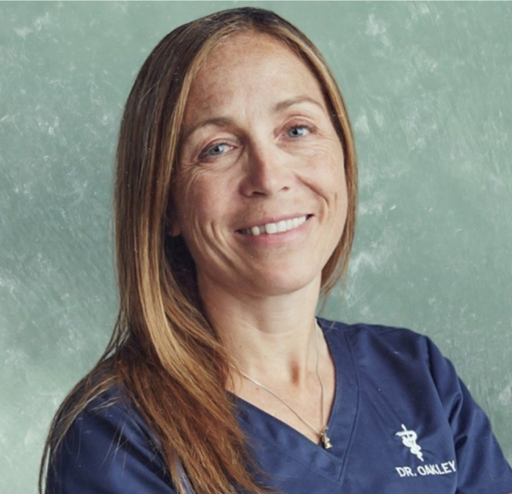 A person in a blue medical uniform smiling against a textured background.